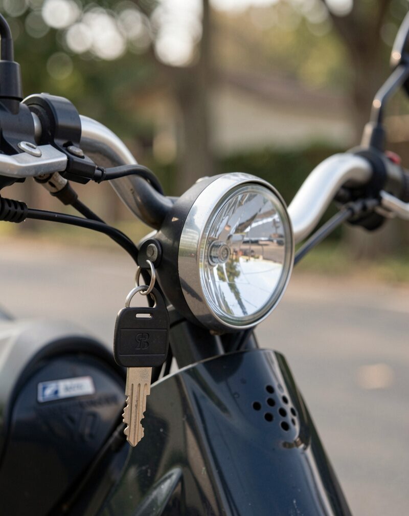 Close-up of a small front lamp clipped to a handlebar beside a lock key